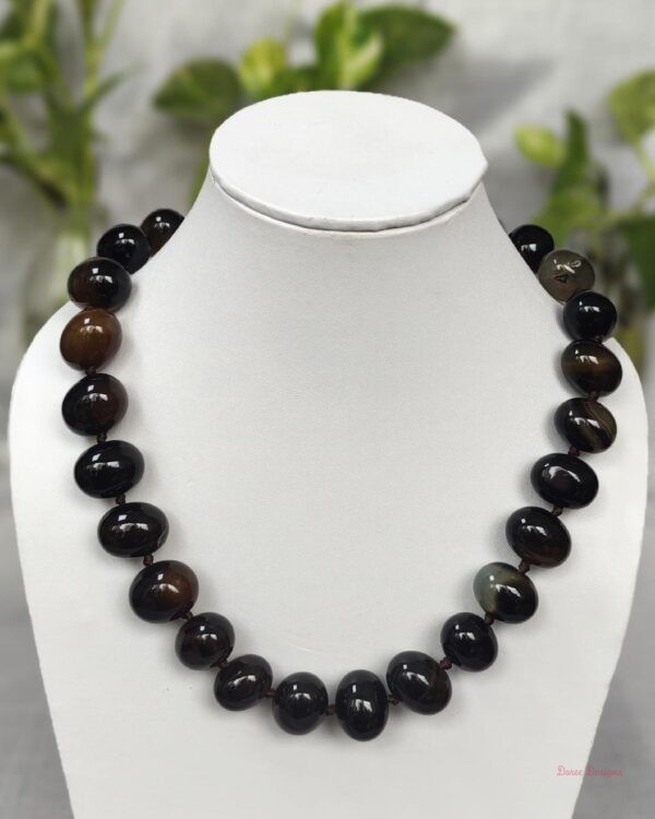 Deep and dark shades of ovoid-shaped chocolate black coloured Onyx tumbles come together in this knotted 19” single strand necklace, with a strong spring-ring clasp for durability DN 0005